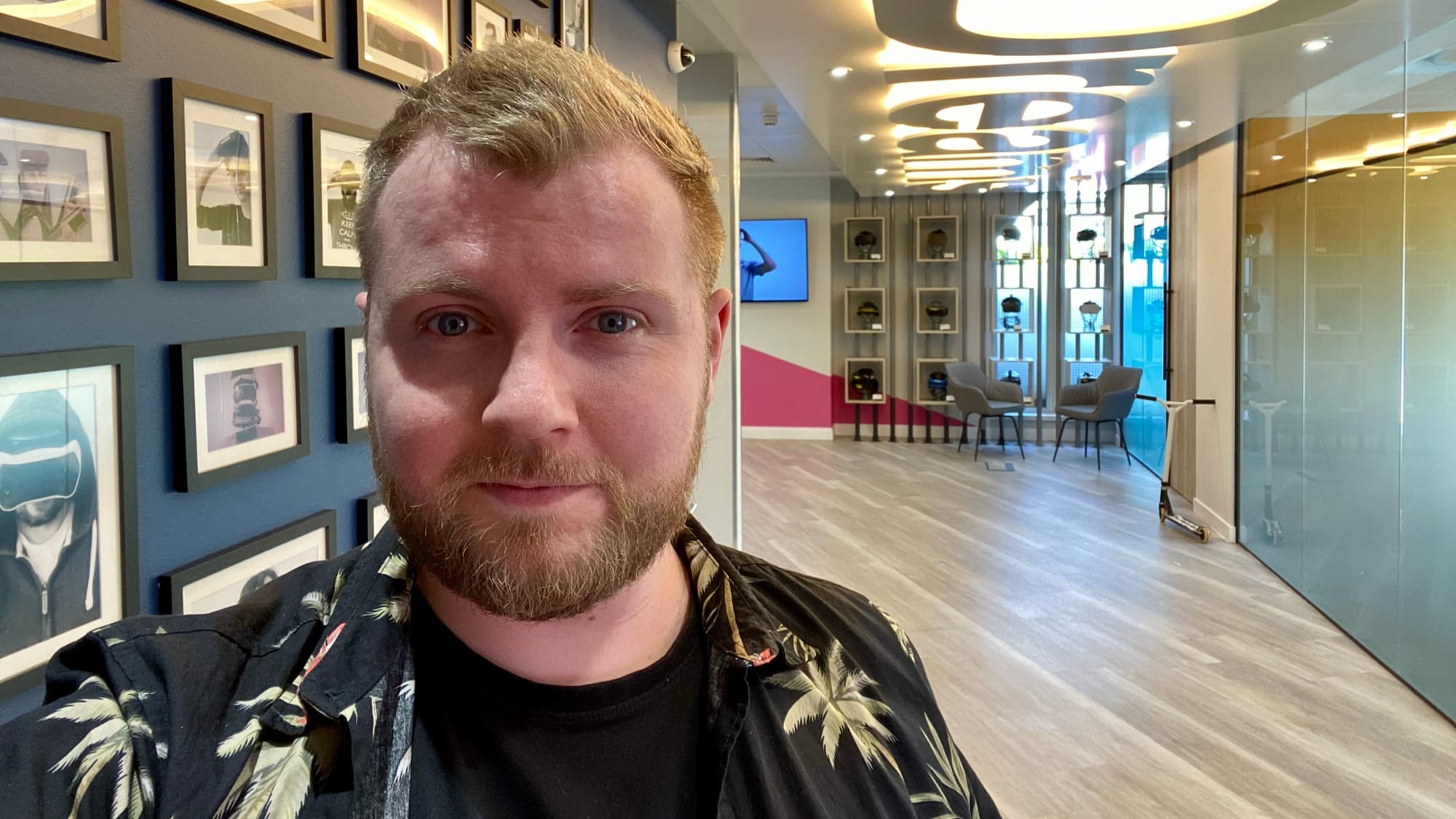 The article's author stood in the entryway of nDreams. A VR headset wall can be seen behind him.